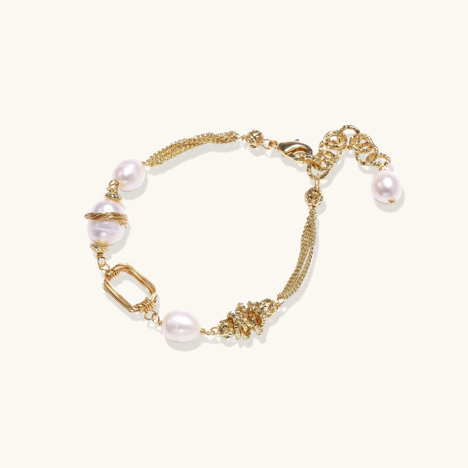 Gold-plated bracelet featuring cream freshwater pearls and decorative chain links on white background.