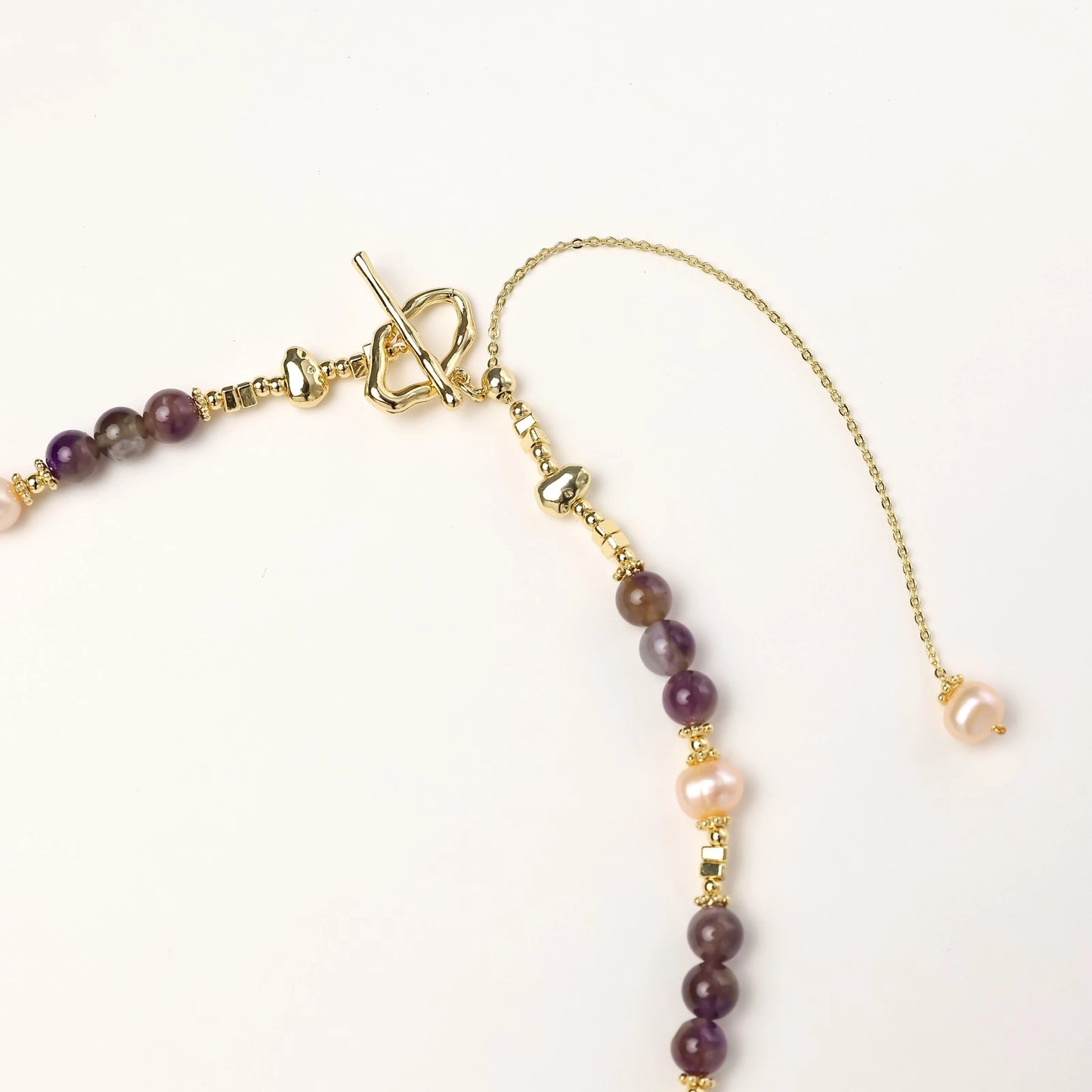 Gold-plated necklace with purple amethyst beads, pink pearls, and iridescent baroque pearl pendant beneath crystal star charm
