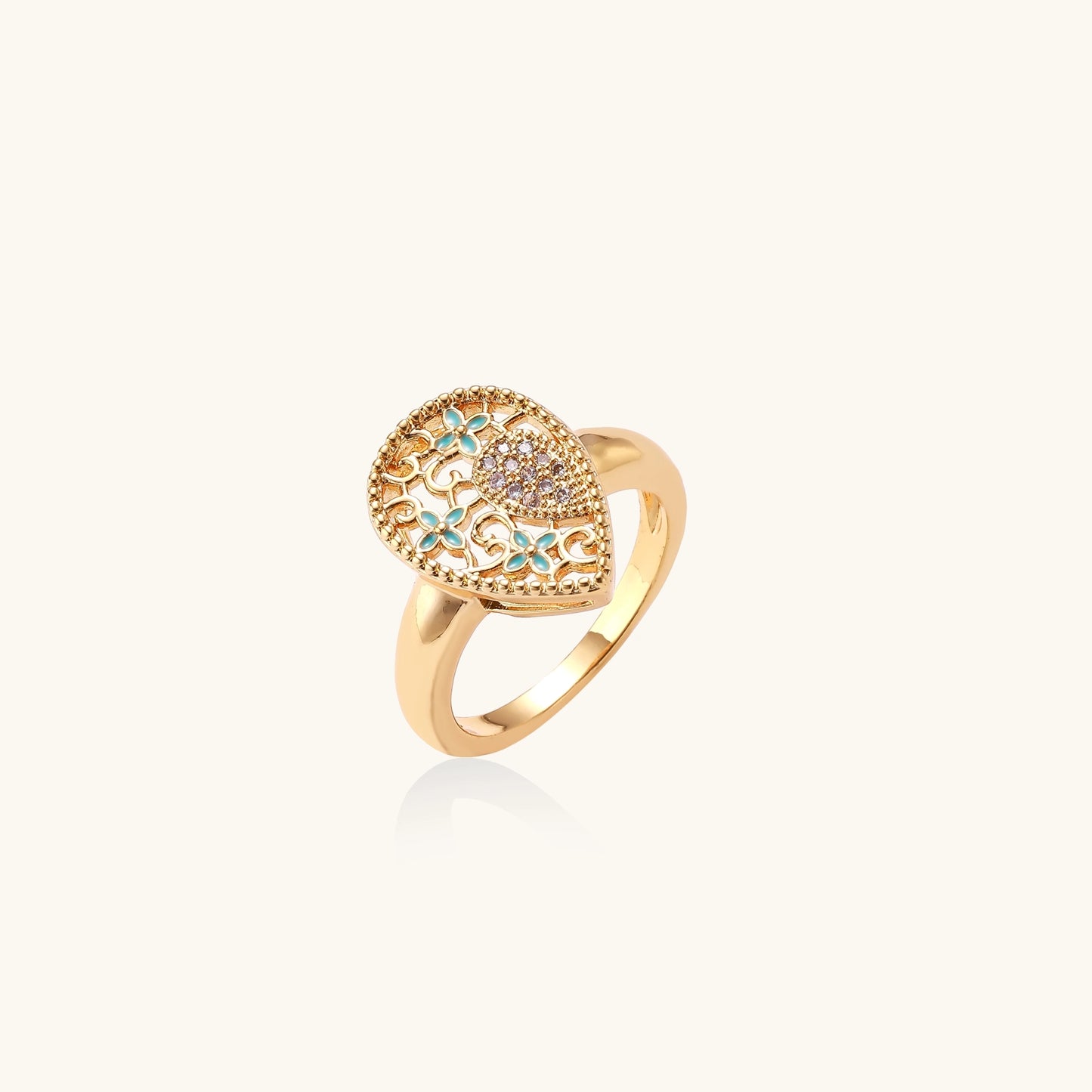 Gold-plated heart ring with turquoise enamel scrollwork and cubic zirconia stones on white background